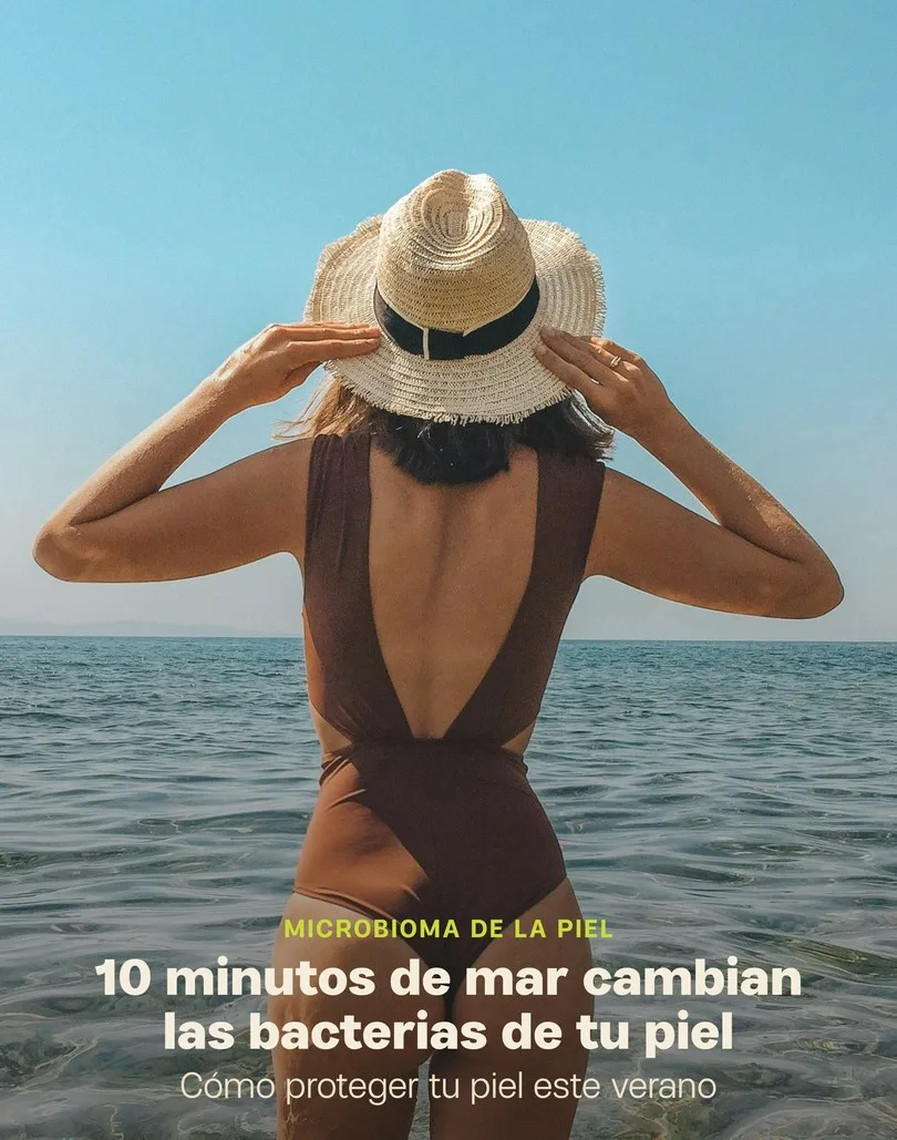 Una mujer de espaldas en el mar, con sombrero de paja, y el texto «10 minutos de mar cambian las bacterias de tu piel».