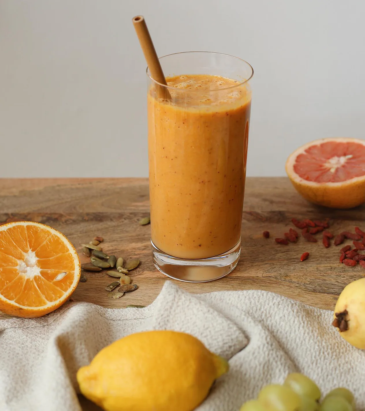 Smoothie color naranja ya servido en casa, entre cítricos.