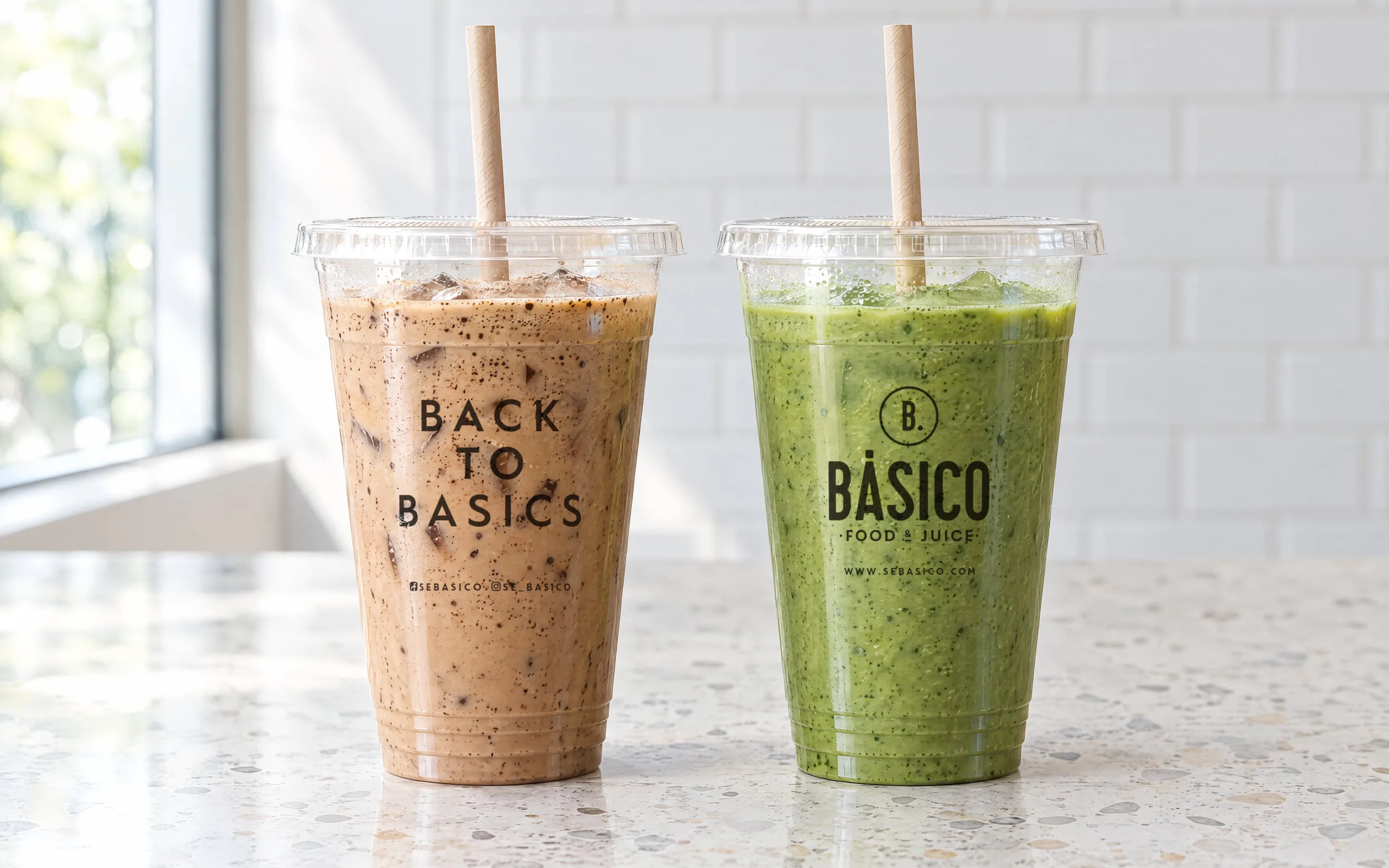 Dos vasos transparentes: un frappé con «Back to Basics» y un smoothie verde con el logotipo de Básico.
