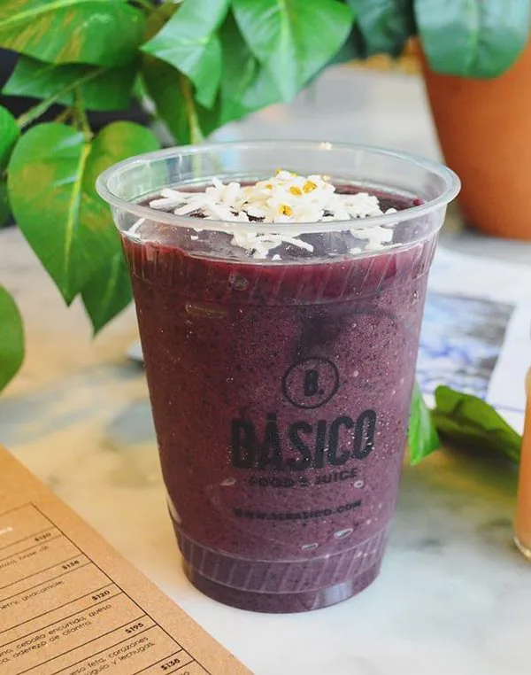 Smoothie morado en vaso transparente con el logotipo de Básico.